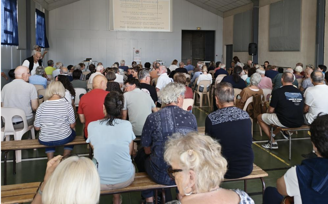 Public réuni dans une salle lors d’une réunion publique à Poey-de-Lescar.
